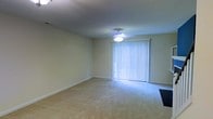 This residential space is distributed across three floors, offering a versatile and functional layout suited for a variety of living arrangements. The interior showcases wall-to-wall carpeting throughout the living areas, providing a comfortable and warm underfoot feel. Neutral-toned walls create a clean, understated backdrop that lends itself well to personalization.

A notable feature of the main living area is the sliding glass door dressed with vertical blinds, allowing for natural light control while offering potential access to an outdoor area. A ceiling fan is centrally mounted overhead, providing both air circulation and ambient lighting to the space. The textured ceiling adds a classic residential character throughout.

The three-floor configuration provides clear separation between living, sleeping, and utility areas, making efficient use of the vertical space. Clean baseboards and smooth wall transitions throughout contribute to a well-maintained and tidy appearance. The overall ambiance is straightforward and practical, offering a neutral canvas that can accommodate a range of interior styles. The multi-level layout ensures that different functions of daily living are well-organized across dedicated floors.
