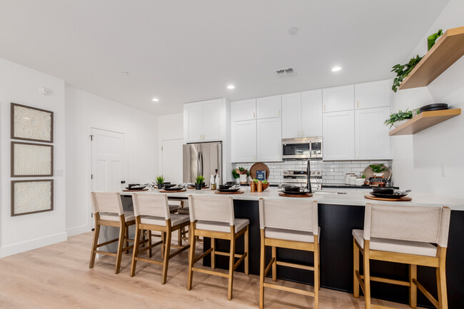 View of kitchen from living room, garage to the left of the fridge - The CJ Luxury Townhomes