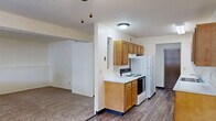 Located at 1845 Winding Hill Rd in Davenport, Iowa, this one-bedroom, one-bathroom unit offers a functional and well-organized single-floor layout. The galley-style kitchen is a standout feature, equipped with warm honey-toned wood cabinetry offering generous upper and lower storage, white appliances including a refrigerator and electric range, a double-basin sink, and a dishwasher. Light-toned laminate wood-style flooring runs throughout the kitchen and hallway areas, lending a clean, cohesive look. Two hallways connect the living and sleeping areas, providing a clear and practical flow through the unit. The spacious living area transitions seamlessly from the kitchen and features plush carpeting. The bedroom is a comfortable, well-proportioned space with soft carpet, a large sliding-door closet, and a window that allows natural light to fill the room. A door from the bedroom leads directly into the full bathroom, which includes a vanity with wood cabinetry and stone-look countertops, a tub-shower combination, and hardwood-style flooring. A louvered closet door in the bathroom provides additional storage. The overall aesthetic is neutral and clean, with light walls and textured ceilings throughout, creating a bright and livable atmosphere.
