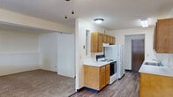 Located at 1845 Winding Hill Rd in Davenport, Iowa, this one-bedroom, one-bathroom unit offers a functional and well-organized single-floor layout. The galley-style kitchen is a standout feature, equipped with warm honey-toned wood cabinetry offering generous upper and lower storage, white appliances including a refrigerator and electric range, a double-basin sink, and a dishwasher. Light-toned laminate wood-style flooring runs throughout the kitchen and hallway areas, lending a clean, cohesive look. Two hallways connect the living and sleeping areas, providing a clear and practical flow through the unit. The spacious living area transitions seamlessly from the kitchen and features plush carpeting. The bedroom is a comfortable, well-proportioned space with soft carpet, a large sliding-door closet, and a window that allows natural light to fill the room. A door from the bedroom leads directly into the full bathroom, which includes a vanity with wood cabinetry and stone-look countertops, a tub-shower combination, and hardwood-style flooring. A louvered closet door in the bathroom provides additional storage. The overall aesthetic is neutral and clean, with light walls and textured ceilings throughout, creating a bright and livable atmosphere.