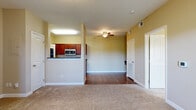 This single-floor residence at 1244 N 129th Terr in Kansas City, KS offers a well-organized open layout that connects the living and kitchen areas seamlessly. The living space features warm-toned carpet, a ceiling fan, and a natural flow into the kitchen via a half-wall pass-through with a dark granite-style countertop. A secondary area with hardwood-style flooring extends the functional living space and provides direct access to the front entry.

The galley-style kitchen is efficiently designed with rich cherry wood cabinetry, dark granite-style countertops, and a full suite of stainless steel appliances including a refrigerator, electric range, microwave, and dishwasher. The layout maximizes storage and prep space along both walls. Adjacent to the kitchen, a dedicated laundry area houses a full-size washer with dryer hookup and overhead storage shelving, adding everyday convenience.

The bedroom is a comfortable, carpet-floored room brightened by a window with outdoor views and equipped with a ceiling fan. The bathroom features matching cherry wood cabinetry, a granite-style vanity countertop, hardwood-style flooring, and a well-lit mirror. Warm neutral tones carry throughout the entire residence, creating a cohesive and inviting atmosphere.