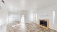 This single-story home offers a well-organized layout designed for comfortable everyday living. The main living area is bright and open, bathed in natural light from multiple windows dressed with blinds. Wood-look flooring runs throughout the common areas, anchored by a tile-surround fireplace with a clean white mantle — a standout architectural feature that adds warmth and character to the space. A pendant light fixture marks the transition into the dining area, which flows naturally from the living room.

The kitchen is efficiently laid out in a U-shape configuration, featuring white cabinetry, laminate countertops, a stainless steel sink, and white appliances including a range, dishwasher, and refrigerator. Wood-look flooring continues here, maintaining visual consistency throughout the home.

Both bedrooms are carpeted and generously proportioned, each equipped with ceiling fans for added comfort. The primary bedroom includes a walk-in closet and direct access to an en-suite bathroom, which features a wide vanity with a large mirror, Hollywood-style lighting, and speckled countertops. A second bathroom offers a tub-shower combination with a window above for natural ventilation, wood-look flooring, and matching speckled countertops. The home's clean, neutral palette throughout makes it a versatile and move-in ready space.