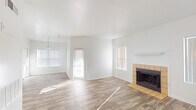 This single-story home offers a well-organized layout designed for comfortable everyday living. The main living area is bright and open, bathed in natural light from multiple windows dressed with blinds. Wood-look flooring runs throughout the common areas, anchored by a tile-surround fireplace with a clean white mantle — a standout architectural feature that adds warmth and character to the space. A pendant light fixture marks the transition into the dining area, which flows naturally from the living room.

The kitchen is efficiently laid out in a U-shape configuration, featuring white cabinetry, laminate countertops, a stainless steel sink, and white appliances including a range, dishwasher, and refrigerator. Wood-look flooring continues here, maintaining visual consistency throughout the home.

Both bedrooms are carpeted and generously proportioned, each equipped with ceiling fans for added comfort. The primary bedroom includes a walk-in closet and direct access to an en-suite bathroom, which features a wide vanity with a large mirror, Hollywood-style lighting, and speckled countertops. A second bathroom offers a tub-shower combination with a window above for natural ventilation, wood-look flooring, and matching speckled countertops. The home's clean, neutral palette throughout makes it a versatile and move-in ready space.