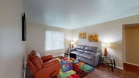 This single-floor residence offers a practical and comfortable layout designed for everyday living. The living room serves as the central gathering space, featuring wood-style flooring, a large window with vertical blinds that allows ample natural light, and a textured ceiling. The open flow leads into a dedicated dining area, also finished with wood-style flooring, a ceiling light fixture, and sliding glass door access that brings in additional natural light.

The galley-style kitchen is lined with dark cabinetry, laminate countertops, and includes a full suite of appliances, providing efficient use of space for meal preparation. Two bedrooms offer comfortable retreats; the primary bedroom features carpeted flooring, a large window with vertical blinds, and ample wall space, while the second bedroom also includes carpet, a sliding glass door to an outdoor area, and a warm, inviting atmosphere.

The residence includes two bathrooms — one with a shower-tub combination featuring white tile surround, and another with a stand-alone shower unit, both with wood-style flooring. Throughout the home, neutral wall tones create a cohesive and versatile backdrop, while consistent finishes tie each room together into a unified, functional living space.