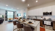 Located at 309 Mirroton Ave in Lakeland, Florida, this modern single-floor residence offers a thoughtfully designed open-concept layout with high-end finishes throughout. The kitchen is a standout feature, boasting floor-to-ceiling white cabinetry, warm wood-toned lower cabinets, a classic white subway tile backsplash, and striking granite countertops. A large island with bar seating flows seamlessly into the living area, making it ideal for entertaining. Stainless steel appliances, including a French door refrigerator, complete the well-appointed kitchen. The living room is bright and welcoming, featuring recessed lighting, large windows that invite natural light, and light-toned flooring that extends throughout the main living spaces. The primary bedroom offers a serene retreat with plush carpeting, generous window coverage, and direct access to an en-suite bathroom. The primary bath features a walk-in tiled shower, a wood-grain vanity with granite countertops, an illuminated mirror, and convenient access to a walk-in closet. A second well-proportioned bedroom also benefits from ample natural light and soft carpeting. The secondary bathroom mirrors the refined aesthetic with a soaking tub, tiled surround, granite vanity, and a backlit mirror. Clean lines and a neutral palette unify the space with a modern, polished ambiance.