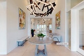 Located at 7607 W Atlantic Ave in Delray Beach, Florida, this elegantly designed amenity facility offers a refined and welcoming atmosphere across a generously proportioned single-floor layout. The grand entrance lobby immediately sets the tone with soaring ceilings, large-format cream tile flooring, and a striking sculptural chandelier composed of intersecting geometric elements. A round textured wood table anchored by a floral arrangement serves as a focal centerpiece, flanked by vibrant abstract artwork and sleek benches.

Flowing from the lobby is an expansive lounge area featuring a dramatic floor-to-ceiling marble stone accent wall with an integrated fireplace. Plush contemporary seating in neutral tones with teal accents creates intimate conversation areas, complemented by slender wall sconces and curated art pieces. Natural light pours in through large glass doors offering outdoor views.

A dedicated game and social room includes a full-sized billiards table, a bar-height counter with multiple flat-screen TVs mounted on a textured feature wall, and direct access to outdoor amenities. Glass-paneled office spaces along an art-lined corridor provide a professional environment with modern furnishings. Throughout, the design maintains a cohesive, upscale aesthetic defined by clean lines, abundant natural light, and carefully selected contemporary décor.