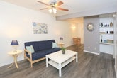 Located at 3002 4th St in Lubbock, Texas, this single-story unit offers a practical and comfortable layout designed for everyday living. The living room sets a welcoming tone with durable wood-look flooring, a ceiling fan with integrated lighting, and a window fitted with blinds and sheer curtains that allow natural light to filter in. A wall-mounted HVAC unit provides climate control directly in the living space.

The kitchen is equipped with a coil-burner electric range, ample upper and lower cabinetry in a warm wood finish, white countertops, and a single-basin sink — offering efficient use of the available space with easy access to an adjoining area.

Both bedrooms feature plush wall-to-wall carpeting and ceiling fans, creating a comfortable retreat. One bedroom includes a walk-in style closet with a built-in rod and shelf, along with space for a dedicated work area. Each room provides a quiet, functional environment suited for rest and productivity.

The full bathroom is finished with tile-accented walls, wood-look flooring, a wall-mounted sink, and a tub-shower combination enclosed by a sliding frosted-glass door, complemented by a well-lit vanity mirror. The overall design of this unit prioritizes functionality and ease of living throughout its compact, single-floor footprint.
