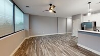 This well-designed 2-bedroom, 1-bathroom unit at 1230 Elm St in Manchester, NH offers a thoughtful layout across a single floor. The open-concept kitchen and living area serves as the heart of the unit, featuring durable hardwood-style plank flooring, recessed lighting, and a ceiling fan. The kitchen is appointed with crisp white shaker cabinets, stainless steel appliances including a French door refrigerator and microwave, a marble-style tile backsplash, and a peninsula with a undermount sink and pendant lighting overhead — ideal for both cooking and casual dining.

The spacious living area benefits from large corner windows that frame views of the surrounding greenery, filling the space with natural light. Both bedrooms feature soft patterned carpeting; the primary bedroom includes a closet with wire shelving, while the second bedroom offers a narrow clerestory window. Each bedroom is finished with neutral gray tones, clean white trim, and built-in closet storage.

The bathroom is efficiently designed with a white vanity featuring a quartz countertop and a large mirror. A standout feature is the in-unit stacked washer and dryer, neatly integrated into a dedicated laundry nook within the bathroom area. Throughout, the unit maintains a clean, modern aesthetic with consistent neutral finishes and thoughtful storage solutions.