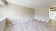 This two-story home offers 3 bedrooms and 2 bathrooms across two floors, with the main level providing the larger share of the overall footprint. The first floor features a living room with light wood-style luxury vinyl plank flooring, a neutral warm-gray color palette, and natural light from front-facing windows. The kitchen is well-appointed with white shaker-style cabinetry, white quartz countertops, stainless steel appliances including a gas range, dishwasher, and refrigerator, a black matte faucet, and a window overlooking greenery. A half bathroom on this level features a gray vanity with a white countertop, black matte fixtures, and a wall-mounted mirror. A staircase connects the two floors, with hallways and two closets providing organized storage throughout. The upper level houses all three bedrooms, including a generously sized primary bedroom with plush carpet flooring, a built-in closet, and access to the full bathroom. The full bathroom includes a tub-shower combination with white tile surround, a gray vanity, and black matte hardware. Secondary bedrooms offer comfortable proportions with soft carpet, neutral walls, and ample natural light.