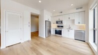 Located at 3150 S Highland Dr in Millcreek, Utah, this efficiently designed single-floor unit offers a clean, contemporary aesthetic throughout. Light-toned hardwood flooring runs continuously across the entire space, creating a cohesive and airy feel.

The kitchen is a standout feature, outfitted with crisp white shaker-style cabinetry, a white subway tile backsplash, and a full suite of stainless steel appliances including a refrigerator, electric range, built-in microwave, and dishwasher. Recessed lighting illuminates the workspace, which also includes a stainless steel sink. The kitchen opens directly to the main living area, promoting an open and functional layout.

The living area benefits from large floor-to-ceiling windows that flood the space with natural light and frame scenic mountain views — a notable feature that adds character and depth to the compact footprint.

The bathroom is well-appointed with a tiled tub-and-shower combination, a warm wood-toned vanity, built-in open shelving for storage, and consistent hardwood-style flooring. Two hallways provide practical circulation and access throughout the unit.

Overall, the space presents a modern, move-in-ready interior with thoughtful finishes, efficient use of space, and appealing natural views of the surrounding Wasatch landscape.