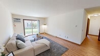 Located at 7733 Carrington Drive in Madison, WI, this single-floor unit offers three bedrooms and one bathroom across a well-utilized layout. The open living room is a standout space, featuring warm hardwood-style flooring, a ceiling fan, and a large sliding glass door that floods the room with natural light and provides views of the surrounding greenery outdoors. The galley-style kitchen is thoughtfully designed with warm wood cabinetry, dark granite countertops, tile flooring, a stainless steel refrigerator, and a double basin sink — offering ample storage and counter space. The bedrooms are carpeted and serene, with the primary bedroom offering a comfortable footprint, a natural-wood door, and a window with outdoor views. The shared full bathroom features tile flooring, a tub-shower combination with tiled surround, a wood-toned vanity, and a light countertop. A dedicated laundry area with a stacked washer and dryer unit adds everyday convenience and connects directly to the bathroom. The neutral color palette and consistent finishes throughout contribute to a cohesive and functional living environment.