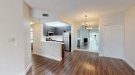 Located at 5540 W Centinela Ave in Los Angeles, CA, this single-floor residence offers a well-designed, open-concept layout that balances modern finishes with functional living spaces. The main living area features rich, dark hardwood flooring that extends throughout, complemented by a textured ceiling and large vertical-blind windows that invite generous natural light and views of the surrounding greenery. A chandelier accent near a mirrored wall adds a refined touch to the dining area. The kitchen is efficiently designed with dark cabinetry, white countertops, and a full suite of stainless steel appliances including a gas range, over-the-range microwave, and refrigerator. A peninsula-style breakfast bar separates the kitchen from the living area, enhancing the open flow of the space. The bedrooms are carpeted and spacious, featuring large windows that bathe each room in natural light. One bedroom includes access to a walk-in closet, providing ample storage. The bathroom is clean and straightforward, featuring a full shower-tub combo with a window for natural ventilation. Overall, the space presents a comfortable, move-in-ready environment with a neutral color palette suitable for a variety of interior styles.