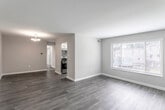 This single-floor residence offers a thoughtfully designed layout with a clean, neutral aesthetic throughout. The open living and dining areas are finished with rich, dark hardwood-style flooring that extends from the entry door through the main living spaces, creating a cohesive and polished look. Large windows dressed with white blinds allow natural light to fill the rooms, offering views of the surrounding exterior.

The kitchen is well-equipped and updated, featuring white cabinetry with brushed nickel hardware, granite-look countertops, a stainless steel single-basin sink with a pull-down faucet, and a mosaic tile backsplash in neutral tones. A stainless steel gas range and under-cabinet range hood complete the functional cooking space.

The bedrooms are carpeted in a warm beige tone, providing comfort underfoot. One bedroom benefits from dual windows that enhance natural light, while another includes a closet with built-in shelving. Neutral-toned walls carry throughout all rooms, lending a calm and versatile backdrop.

The bathroom is finished with wood-style flooring, a white vanity with an integrated sink, and a window that brings in additional natural light. The overall ambiance of the space is clean, bright, and move-in ready.