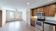This single-floor residential unit offers a thoughtfully designed layout that balances functionality and comfort. The kitchen is a standout feature, equipped with rich warm-toned cabinetry, granite countertops, a white subway tile backsplash, and a full suite of stainless steel appliances including an electric range, over-the-range microwave, dishwasher, and refrigerator. Recessed lighting and wood-look plank flooring throughout the kitchen and living areas add a clean, modern aesthetic.

The open living area flows naturally from the kitchen, bathed in natural light from double windows fitted with horizontal blinds. A ceiling fan overhead provides year-round comfort in this space. The transition from the main living area to the bedroom is smooth, with the bedroom offering plush carpeting, a ceiling fan with integrated lighting, and a window that lets in ample natural light.

The bathroom is well-finished, featuring a tub-shower combination with white subway tile surround, a granite-topped vanity with an undermount sink, brushed nickel hardware, and tile flooring. Throughout the unit, consistent design choices—granite surfaces, warm wood cabinetry, and neutral wall tones—create a cohesive and inviting atmosphere.
