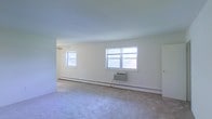 Located at 760 Eayrestown Road in Lumberton, New Jersey, this single-floor residence offers a clean and functional layout well-suited for comfortable everyday living. The interior is characterized by neutral, light-toned walls that create a bright and airy atmosphere throughout. The main living area is generously proportioned, featuring soft carpet flooring that adds warmth underfoot. Multiple windows allow abundant natural light to fill the room, contributing to an open and welcoming feel. A window-unit air conditioner provides cooling during warmer months, while baseboard heating runs along the perimeter of the room for efficient warmth in cooler seasons. The space is move-in ready with a straightforward, uncluttered design that provides a neutral canvas for personalization. The single-story layout ensures ease of accessibility and seamless flow throughout the home. Situated in Lumberton, NJ, the property benefits from a quiet, residential setting while remaining conveniently accessible to local amenities and major roadways in Burlington County.