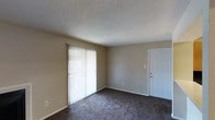 This single-floor residence features two bedrooms and two bathrooms within a well-organized and efficient layout. The living area is finished with wall-to-wall carpeting in a neutral dark tone, complemented by beige walls that create a warm, understated ambiance throughout. A textured popcorn ceiling adds a classic touch to the interior. Natural light enters generously through a large sliding glass door fitted with vertical blinds, brightening the main living space and providing access to the outdoors. A dedicated entry door with a brass-toned handle offers a welcoming entryway directly into the living area. The open feel of the main room provides a versatile space suitable for a variety of furniture arrangements. The neutral color palette throughout makes it easy to personalize the interior with different décor styles. With two full bathrooms and two bedrooms, the floor plan is well-suited to support both shared living and individual privacy. The single-level design ensures convenient, step-free access throughout the entire residence, making it a functional and comfortable living option.