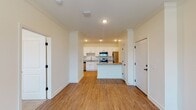 This single-floor residence offers a clean, modern layout designed for comfortable everyday living. The open-concept living and kitchen area serves as the heart of the home, where light hardwood-style flooring flows seamlessly throughout. The kitchen is outfitted with crisp white shaker cabinetry, granite countertops, a central island for additional prep and seating space, and a full suite of stainless steel appliances including a range, over-the-range microwave, dishwasher, and refrigerator. Recessed lighting illuminates the kitchen area, adding a polished touch.

The living spaces are defined by consistent crown molding along the ceilings and ceiling fans with integrated lighting, contributing to both style and comfort. Multiple rooms feature natural light through horizontal-blind-covered windows with views of the surrounding greenery. Bedrooms are finished with plush neutral carpet, while other areas maintain the hardwood-style flooring for easy maintenance.

The bathroom includes a full tub-shower combination with built-in shelving, granite-topped vanity, and hardwood-style flooring. Throughout the residence, white panel doors with matte black hardware provide a cohesive and contemporary aesthetic, rounding out a well-designed and functional living space.