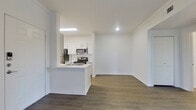 This single-floor unit offers a clean, modern aesthetic with a thoughtfully designed open-concept layout. The kitchen is a standout feature, outfitted with crisp white cabinetry, stainless steel appliances including a refrigerator, electric range, and over-the-range microwave, and a peninsula island with a sink that flows seamlessly into the living area. Wood-look flooring runs throughout the main living spaces, adding warmth and visual continuity, while crown molding along the ceilings lends a refined touch. The living area is generously sized, bathed in natural light from a sliding glass door fitted with vertical blinds, and accented by a ceiling fan overhead.

The bedrooms are carpeted for comfort and feature ceiling fans, large windows with blinds that invite ample natural light, and access to closet space. The primary bedroom includes an en-suite bathroom and an additional closet. The bathroom is well-appointed with white cabinetry, a light countertop with an undermount sink, a framed mirror, and a full tub-shower combination with tile surround. Throughout the unit, the bright white walls and neutral palette create a light, airy atmosphere that is both welcoming and versatile.