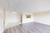 This thoughtfully designed 2-bedroom, 2-bathroom residence in Belmont, MA presents a clean, modern aesthetic throughout its single-floor layout. The open-concept living and dining area is a standout feature, combining light wood-tone flooring with neutral cream walls to create a bright, welcoming atmosphere. A pass-through window connects the living space to the kitchen, which is equipped with white cabinetry, granite-style countertops, stainless steel appliances including a full-size refrigerator, and light tile flooring. The living area features a sliding glass door that opens to an outdoor balcony, filling the space with natural light and providing exterior views. Both bedrooms are generously proportioned, featuring the same warm wood-tone flooring, with the primary bedroom offering ample square footage and a large window overlooking the surrounding neighborhood. Four closets throughout the unit provide abundant storage. The two bathrooms are finished with white tile flooring, white vanity cabinetry, granite-style countertops, and a full tub-shower combination with clean white tile surround. A connecting hallway ties the layout together efficiently, making this a well-organized and functional home.