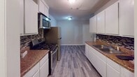 This single-story home at 405 Hale St in Augusta, Georgia, offers a thoughtfully updated interior with a clean, cohesive aesthetic throughout. Durable wood-look plank flooring and neutral warm-gray walls are consistent across the living areas, bedrooms, and kitchen, creating a unified and modern feel.

The galley-style kitchen is well-appointed with white shaker cabinetry, dark granite-style countertops, a mosaic tile backsplash, and a full suite of stainless steel appliances including a gas range, over-the-range microwave, and refrigerator. The layout provides ample counter and storage space, with room for casual dining adjacent to the kitchen area.

The bedrooms are comfortably proportioned, each featuring ceiling fans with light fixtures and window blinds that allow for natural light. At least one bedroom includes a closet with a built-in rod and shelf. A dedicated laundry room is equipped with washer and dryer hookups, including both water supply connections and a dryer vent, offering added convenience.

The bathroom is cleanly finished with matching wood-look tile flooring, a tub/shower combination with a curved curtain rod, a toilet, and a single vanity. Textured ceilings are present throughout, and white panel doors and trim provide a crisp contrast to the neutral wall tones. This home presents a well-maintained, move-in-ready option in Augusta.