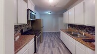 This single-story home at 405 Hale St in Augusta, Georgia, offers a thoughtfully updated interior with a clean, cohesive aesthetic throughout. Durable wood-look plank flooring and neutral warm-gray walls are consistent across the living areas, bedrooms, and kitchen, creating a unified and modern feel.

The galley-style kitchen is well-appointed with white shaker cabinetry, dark granite-style countertops, a mosaic tile backsplash, and a full suite of stainless steel appliances including a gas range, over-the-range microwave, and refrigerator. The layout provides ample counter and storage space, with room for casual dining adjacent to the kitchen area.

The bedrooms are comfortably proportioned, each featuring ceiling fans with light fixtures and window blinds that allow for natural light. At least one bedroom includes a closet with a built-in rod and shelf. A dedicated laundry room is equipped with washer and dryer hookups, including both water supply connections and a dryer vent, offering added convenience.

The bathroom is cleanly finished with matching wood-look tile flooring, a tub/shower combination with a curved curtain rod, a toilet, and a single vanity. Textured ceilings are present throughout, and white panel doors and trim provide a crisp contrast to the neutral wall tones. This home presents a well-maintained, move-in-ready option in Augusta.