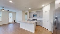 This well-designed two-story home offers five bedrooms and four bathrooms across a thoughtfully laid-out floor plan. The main level provides the larger share of living space and centers around an open-concept kitchen and living room. The kitchen is a standout feature, boasting a granite-topped center island with an integrated sink, grey shaker-style cabinetry, a subway tile backsplash, and a full suite of stainless steel appliances including a gas range, microwave, and refrigerator. Light wood-look flooring flows throughout the main level, complemented by recessed lighting and a clean, neutral color palette that enhances the sense of openness.

The upper floor houses the majority of the bedrooms, connected by a bright hallway with recessed lighting. The generously sized primary bedroom features multiple windows that invite natural light, a ceiling fan, and access to a walk-in closet with dual hanging rods and built-in shelving. Secondary bedrooms are finished with plush carpet, ceiling fans, and windows with blinds. A dedicated laundry room with overhead cabinetry and a full-size washer and dryer adds everyday convenience. Throughout the home, the consistent use of light tones, modern hardware, and clean architectural lines creates a fresh and functional living environment.