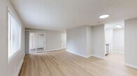 Located at 4601 East 18th Street in Vancouver, WA, this two-bedroom, one-bathroom unit offers a thoughtfully organized single-floor layout. Light wood flooring runs throughout the entire space, complementing neutral gray walls and crisp white trim to create a clean, contemporary aesthetic. Textured ceilings add a classic touch across all rooms.

The open-concept living and kitchen area is bright and inviting, with natural light flowing in through large windows and a sliding glass door. Baseboard heating units run along the walls, ensuring year-round comfort. The kitchen is well-appointed with white shaker cabinetry, gray countertops, a white tile backsplash, and stainless steel appliances including a range and dishwasher.

Both bedrooms are comfortably sized, with the primary bedroom offering a generous footprint and a dedicated closet. The second bedroom connects easily to the main hallway. In total, the unit features four closets, providing ample storage throughout. The bathroom includes a wide vanity with white cabinetry, gray countertops, a large mirror, and modern light fixtures. A dedicated utility closet houses the water heater. The surrounding landscape, visible from the windows, includes mature trees that enhance the sense of a peaceful residential setting.