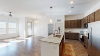 This single-floor residence offers a thoughtfully designed open-concept layout that seamlessly connects the kitchen, dining, and living areas. The kitchen is a standout feature, showcasing rich dark-brown cabinetry that extends to the ceiling, a large granite-topped island with a double sink and pendant lighting overhead, and a full suite of stainless steel appliances including a refrigerator with ice maker, range, and microwave. Wood-style flooring flows consistently throughout the entire space, complementing the clean white walls and creating a warm, cohesive aesthetic.

The living area is generously proportioned, bathed in natural light from large windows fitted with blinds, and equipped with a ceiling fan. Each bedroom continues the same bright, airy character, featuring wood-style floors, ceiling fans, and wide windows that invite abundant daylight. The primary bedroom includes direct access to a walk-in closet with built-in shelving and hanging rods.

Two full bathrooms serve the residence. The primary bathroom features a dual-sink vanity with granite countertops, dark wood cabinetry, a walk-in glass shower, and a separate water closet. The secondary bathroom mirrors this refined aesthetic with a granite vanity, dark cabinetry, and a shower-tub combination. Together, the spaces deliver a clean, modern, and functional living environment.
