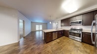 Located at 55 Maria Dr in Petaluma, CA, this single-floor residence offers four bedrooms, two bathrooms, a living room, dining room, and kitchen thoughtfully arranged in a well-utilized layout. The open-concept kitchen serves as the heart of the home, featuring rich dark-espresso cabinetry, a large center island with a light quartz countertop, a stainless steel dishwasher, gas range, microwave, and refrigerator. Elegant pendant lighting hangs above the island, adding a modern touch. Hardwood-style flooring extends throughout the main living areas, while the living room opens directly to a private balcony through glass French doors, offering views of the surrounding Petaluma neighborhood. The bedrooms are carpeted and filled with natural light through blinds-fitted windows, providing a warm and comfortable retreat. The primary bedroom offers a generous footprint with ample space. The bathrooms are finished with dark cabinetry, light quartz countertops, and hardwood-style flooring consistent with the rest of the home. One bedroom features track lighting and hardwood-style flooring, offering flexibility as an office or creative space. Clean neutral walls and consistent finishes throughout give the home a cohesive, modern aesthetic.