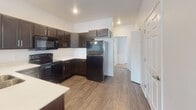Located at 6015 W Yukon Trail in Sioux Falls, South Dakota, this single-level residence offers a well-organized layout designed for comfortable everyday living. The kitchen serves as a functional centerpiece, featuring dark espresso-toned shaker-style cabinetry with brushed nickel hardware, light countertops, and a full suite of black appliances including a range, over-the-range microwave, and refrigerator. Wood-look flooring runs throughout the kitchen, adding warmth and durability to the space. Recessed lighting illuminates the area, and an adjacent hallway connects the kitchen to the rest of the home.

The bedrooms are finished with neutral-toned carpeting and feature windows fitted with blinds that provide views of the surrounding neighborhood and allow natural light to fill the rooms. The clean white walls and simple trim throughout contribute to a bright, move-in-ready aesthetic.

Two bathrooms serve the home. One includes a soaking tub and shower combination with brushed nickel fixtures and wood-look tile flooring, while the second features a standalone walk-in shower with a clean white surround. Both bathrooms maintain a consistent, understated design. Overall, the home presents a straightforward, modern interior with practical finishes throughout.