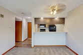 Located at 6521 Vine St in Lincoln, Nebraska, this one-bedroom, one-bathroom unit offers a practical and well-organized layout across a single floor. The living area features neutral-toned carpet, warm wood baseboard trim, and a ceiling fan with light fixture, creating a simple yet comfortable atmosphere with a textured ceiling overhead. A pass-through counter connects the living space to the kitchen, which is laid out in a galley style with wood-toned cabinetry, light countertops, and a full suite of black appliances including a refrigerator, electric range, microwave, and dishwasher. Wood-look flooring runs throughout the kitchen, adding a clean, durable surface underfoot. The bedroom is a comfortably sized retreat with plush carpet, a ceiling fan, a window with blinds that allows natural light, and warm wood-toned closet doors providing ample storage. An additional closet is also present in the bedroom area. The bathroom is clean and functional, featuring a full-size tub and shower combination with chrome fixtures. A hallway connects the rooms and adds to the efficient flow of the layout. This unit offers a straightforward, well-appointed living space in a convenient Lincoln location.