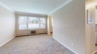 Located at 655 Larpenteur Ave W in Roseville, Minnesota, this single-floor unit offers a practical and comfortable layout designed for everyday living. The spacious living area features neutral-toned carpet, soft wall colors, and a large multi-pane window that invites generous natural light and exterior views, creating an open and airy atmosphere. Baseboard heating and a wall-mounted air conditioning unit provide year-round climate control. The bedrooms are carpeted and well-proportioned, each featuring windows with blinds that allow for natural light and outdoor views of the surrounding neighborhood. The kitchen is equipped with white cabinetry, a double-basin sink, laminate countertops, and durable tile flooring, providing ample storage and workspace. Adjacent to the kitchen is a dining or utility area with matching tile flooring and an additional window overlooking the outdoors. The bathroom features classic yellow wall tile surrounding a full bathtub, a mosaic tile floor, a vanity with mirror, and overhead lighting. Throughout the unit, a consistent neutral color palette and clean finishes contribute to a cohesive and move-in-ready environment. The overall layout, as seen in the dollhouse view, is well-organized and efficiently designed for comfortable single-level living.
