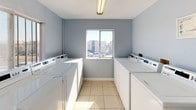 This single-floor shared laundry facility is designed for efficiency and ease of use. The room features a symmetrical layout, with rows of white commercial-grade washing machines and dryers lining both sides of the space, providing ample capacity for multiple users. The light gray walls and beige ceramic tile flooring give the room a clean, neutral aesthetic that is both functional and welcoming. A centrally positioned window on the far wall allows natural light to fill the space, creating a bright and airy atmosphere while offering a view of the surrounding exterior. Overhead fluorescent lighting ensures the room remains well-lit at all times. The layout maximizes the available floor space, leaving a clear central walkway for easy access to all machines. The room's straightforward, utilitarian design prioritizes practicality, making it a convenient and accessible amenity. Overall, this laundry facility is a well-maintained, thoughtfully arranged space that serves its purpose with clarity and simplicity.