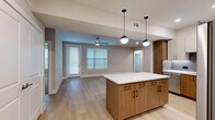 Located at 7777 Manderville Ln in Dallas, Texas, this single-story, 3-bedroom, 3-bathroom home offers a thoughtfully designed open-concept layout with modern finishes throughout. The combined kitchen and living area serves as the heart of the home, featuring light wood-look flooring, neutral gray walls, and abundant natural light from multiple windows with blinds. A ceiling fan anchors the living space, adding comfort and a casual, airy feel.

The kitchen is a standout, showcasing a large center island with a white quartz countertop and warm wood cabinetry, complemented by pendant globe lighting overhead. Full-height upper cabinets in a two-tone white and wood-grain finish frame stainless steel appliances, including a refrigerator, range, and microwave. A subway tile backsplash adds texture and contemporary appeal.

The primary bedroom offers plush carpeting, a ceiling fan, and direct access to a private en-suite bathroom featuring warm wood vanity cabinetry. Additional bathrooms include a tiled shower with glass enclosure and a separate tub-shower combo with white subway tile surround. The bedrooms are finished with soft carpet, and the two closets include wire shelving systems for organized storage. The overall ambiance is clean, modern, and move-in ready.