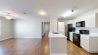 Located at 2909 Minnesota Ave in Lynn Haven, Florida, this single-floor, 2-bedroom, 3-bathroom home offers a well-organized and functional layout. Rich wood-look flooring runs throughout the main living areas and bedrooms, providing a warm and cohesive aesthetic.

The open-concept kitchen and living room serve as the heart of the home. The kitchen features white cabinetry, a large center island with a built-in sink and white countertops, black appliances including a refrigerator, range, and microwave, and a pendant light fixture that adds a modern touch. The adjoining living area is bright and airy, benefiting from natural light through a window framed with blinds and a ceiling fan overhead.

The primary bedroom is generously sized, featuring a ceiling fan, a window with outdoor views, and access to a walk-in closet outfitted with wire shelving on three walls and hardwood-style flooring — offering ample storage and organization. The three bathrooms include white vanities and tile flooring, maintaining a clean and consistent design throughout.

Additional spaces include a dedicated laundry area, a hallway connecting the rooms, and a second bedroom with its own lighting fixture. Neutral wall tones and clean finishes throughout create a bright, move-in-ready atmosphere well-suited for everyday living.
