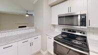 This well-appointed 2-bedroom, 2-bathroom single-story home in Greensboro, NC offers a thoughtfully designed layout with a clean, contemporary aesthetic throughout. The open kitchen is a standout feature, showcasing crisp white shaker cabinetry, marble-look countertops, classic subway tile backsplash, and a full suite of stainless steel appliances including a refrigerator, range, microwave, and dishwasher. Light wood-look flooring ties the kitchen seamlessly into the adjacent living area. The spacious living room is highlighted by crown molding, a ceiling fan, a tiled fireplace, and sliding glass doors that open to an outdoor balcony area, filling the room with natural light and greenery views. Both bedrooms are carpeted and generously sized, with large windows that invite in natural light. The primary bedroom benefits from direct outdoor access via sliding glass doors. A dedicated closet provides practical storage. The two bathrooms are finished with white vanities featuring stone-look countertops and tub-shower combinations. A connecting hallway provides smooth flow between all areas of this comfortable, move-in ready home.