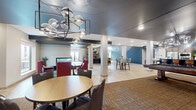 Located at 120 Summit St in Duluth, Minnesota, this single-floor community amenity space offers a generously sized, thoughtfully designed environment ideal for socializing, relaxing, and recreation. The open layout is anchored by light hardwood flooring that flows throughout, unifying a series of distinct yet interconnected zones.

The main lounge area features dramatic coffered ceilings with warm wood inlays and bold dark beams, complemented by a statement globe chandelier and a large wall-mounted television set above a fireplace. A striking large-scale Duluth city map mural adorns one wall, adding a locally inspired artistic touch. Comfortable sectional seating, patterned area rugs, and curated accent chairs create an inviting gathering space.

A dedicated dining and co-working zone offers bar-height seating, communal tables, and abundant natural light from large windows. An intimate lounge nook features curved, leather banquette seating with decorative hexagonal tile wall art and ambient under-seat lighting for a more private retreat.

The space also includes a fully equipped communal kitchen with stainless steel appliances, warm wood cabinetry, and stylish pendant lighting. A game room with a foosball table, gallery wall art, and circular ceiling fixtures rounds out the amenities. The overall ambiance is modern, vibrant, and community-focused with a cohesive design palette of navy, green, and warm wood tones.