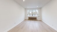 This thoughtfully laid-out 1-bedroom, 1-bathroom unit offers a clean, modern aesthetic throughout its single floor. Light-toned hardwood flooring flows seamlessly across all rooms, creating a bright and cohesive atmosphere. The entry hallway provides a welcoming transition into the main living areas, with clean white walls and efficient use of space.

The living room is generously proportioned, featuring recessed lighting and a large window fitted with a classic cast-iron radiator, flooding the room with natural light and views of the surrounding neighborhood. Adjacent to the living area, the kitchen is well-equipped with white shaker-style cabinetry extending to the ceiling, a white subway tile backsplash, stainless steel appliances including a range, over-the-range microwave, and refrigerator, as well as a window that brings in additional natural light.

The bedroom offers a comfortable footprint, complete with a built-in closet, a large window with a radiator beneath it, and the same light hardwood flooring found throughout. The bathroom features a full tub-shower combination with white subway tile surround, a vanity with sink, and a clean, functional design. A dedicated hallway connects all rooms efficiently, completing this practical and stylish layout.