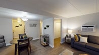 Located at 1711 Lafayette Ave in Kalamazoo, Michigan, this single-floor unit offers a well-organized layout designed for comfortable everyday living. The living room serves as a central gathering space, featuring wood-look flooring, neutral gray walls, and a large sliding glass door fitted with vertical blinds that allows natural light to fill the room. A wall-mounted air conditioning unit and baseboard heating provide year-round climate control.

The adjacent dining area flows naturally from the living space, sharing the same hardwood-style flooring and maintaining a cohesive, open feel. The kitchen is outfitted with dark cabinetry, granite-style countertops, and standard appliances, offering a functional cooking environment.

Two bedrooms are carpeted and finished with neutral tones. The primary bedroom accommodates a full-size bed and features a window that brings in natural light. The second bedroom comfortably fits two twin beds, also with a window providing additional brightness.

The bathroom includes a double-sink vanity with a wide mirror, white tile wainscoting, wood-look flooring, and a bathtub with a shower curtain, delivering a clean and practical design throughout.