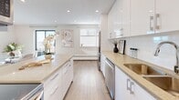 Located at 2380 Marine Drive in Oakville, Ontario, this well-appointed 2-bedroom, 1-bathroom unit offers a thoughtfully designed single-floor layout with a clean, contemporary aesthetic throughout. Light hardwood flooring flows seamlessly across the entire space, complemented by neutral warm-toned walls that create a bright and cohesive atmosphere.

The open-concept kitchen is a standout feature, showcasing sleek high-gloss white cabinetry extending to the ceiling, stone countertops, a white tile backsplash, and a full suite of stainless steel appliances including a refrigerator, dishwasher, and range. A central island provides additional prep space and connects naturally to the living and dining areas. Recessed lighting illuminates the kitchen and living room, which receives generous natural light through multiple windows.

The spacious primary bedroom offers a comfortable and tranquil retreat with hardwood flooring, a large window, and a wall-mounted mini-split unit for individual climate control. The second bedroom is equally versatile, featuring its own window and mini-split system. The bathroom is finished with large-format tile, a glass-enclosed walk-in shower, and a modern white vanity with integrated storage. A hallway connects all rooms efficiently, completing this well-organized and stylish home.