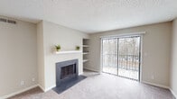 Located at 229 Wind Rd in Greensboro, NC, this single-floor residence offers a thoughtfully designed layout with a warm, neutral aesthetic throughout. The living room serves as the heart of the home, anchored by a classic fireplace with a clean white mantel and flanked by built-in shelving for display and storage. Large sliding glass doors flood the space with natural light and open to a private balcony overlooking a serene, wooded backdrop. Soft carpeting adds comfort underfoot in the living and bedroom areas.

The galley-style kitchen is both functional and stylish, featuring granite countertops, crisp white cabinetry with brushed nickel hardware, a white subway tile backsplash, and stainless steel appliances. Light wood-look flooring runs through the kitchen and into a flexible adjoining space, ideal for use as a dining area. The bedroom is a quiet, carpeted retreat with neutral walls and ample room for furnishings. The bathroom is clean and practical, outfitted with a full tub-and-shower combination. Throughout the space, textured ceilings, clean white trim, and a cohesive neutral palette create a bright and inviting atmosphere.