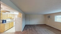 This single-floor residential unit offers a practical and well-organized layout designed for comfortable everyday living. The living area is generously sized, featuring wall-to-wall carpeting, neutral-toned walls, and a wide horizontal window that allows natural light to fill the space. A baseboard heating system and a wall-mounted air conditioning unit ensure year-round climate control throughout the unit.

The galley-style kitchen is efficiently designed with light wood cabinetry, granite-look countertops, a double-basin sink, and white appliances including a refrigerator, dishwasher, and range. Light tile flooring provides a clean, easy-to-maintain surface in this area.

The bedrooms are carpeted and feature textured ceilings, neutral walls, and windows that bring in natural light and outdoor views. Baseboard heaters line the perimeter of each room, ensuring consistent warmth. The rooms offer a quiet, functional space suitable for a variety of arrangements.

The bathroom is straightforward and clean, equipped with a full-size soaking tub and an integrated tub-surround with a shower curtain rod, along with a standard toilet. The overall ambiance of the unit is understated and move-in ready, with a neutral palette throughout that provides a versatile backdrop for personalization.