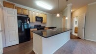 Located along Arden Creek Lane in Charlottesville, Virginia, this single-floor residence offers a well-organized layout designed for comfortable everyday living. The open-concept design connects the kitchen and living areas seamlessly, creating a spacious and functional core within the home.

The kitchen is a standout feature, equipped with light wood cabinetry accented by crown molding, dark granite countertops, and black appliances including a refrigerator, range, and built-in microwave. A peninsula with an integrated sink extends into the living space, providing additional prep area and casual seating. Pendant lighting above the peninsula adds both task illumination and visual interest.

The living area is generously sized, finished with neutral carpet and crown molding details. Multiple windows along one wall, along with a glass-paneled exterior door, allow natural light to fill the space and offer views of the surrounding greenery.

The bedrooms are carpeted and feature windows that bring in natural light, maintaining the home's bright and airy feel. The bathrooms are finished with tile flooring, tile-surround tub and shower combinations, warm wood vanity cabinetry, and large mirrors. One bathroom also provides access to a walk-in closet.

Overall, the unit presents a clean, functional aesthetic with consistent finishes throughout.