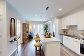 Located at Fox Valley Center Drive in Aurora, IL, this well-appointed 2-bedroom, 2-bathroom residence offers a thoughtfully designed open-concept layout across a single floor. The combined kitchen and living area serves as the heart of the home, anchored by a sleek kitchen featuring white flat-front cabinetry extending to the ceiling, dark quartz countertops, a neutral tile backsplash, and a full suite of stainless steel appliances including a gas range, microwave, and French door refrigerator. A center island with a light stone countertop provides additional prep space and casual bar seating. Rich hardwood-style flooring flows throughout the main living areas, complementing the bright, neutral palette. The living room opens directly to a private balcony through sliding glass doors, offering views of the community courtyard and pool below. The spacious primary bedroom features plush carpet, a large window for natural light, and its own dedicated closet. The second bedroom is equally well-lit with a large window and a distinctive decorative accent wall. Both bathrooms are finished with modern fixtures, including a glass-enclosed shower, wood-look tile flooring, dark countertops, and framed mirrors. Two closets provide ample storage throughout the residence.