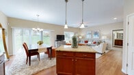 This thoughtfully designed 2-bedroom, 2-bathroom single-floor residence offers a comfortable and functional layout with a seamless open-concept living space at its heart. The kitchen is a standout feature, showcasing rich cherry wood cabinetry, granite countertops, stainless steel appliances including a refrigerator, range, and built-in microwave, and warm hardwood flooring. A granite-topped center island adds both prep space and visual appeal.

The kitchen flows effortlessly into the combined dining and living area, where a sliding glass door fills the space with natural light and provides views of a lush green outdoor landscape. A ceiling fan, pendant lighting, and a chandelier over the dining area contribute to the warm, inviting ambiance.

The living room features recessed lighting and is spacious enough to accommodate a generous seating arrangement. The primary bedroom is a well-proportioned retreat with carpeted flooring and a dedicated walk-in closet with wire shelving. The second bedroom also features carpet and a window with natural light. Both bathrooms include cherry wood vanities with granite countertops and hardwood flooring. A dedicated laundry room houses a full-size washer and dryer, completing this practical and stylish home.