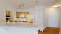 Located at 4510 Tesla Park Dr in Wilmington, NC, this single-floor residence offers a well-organized, functional layout with a clean, neutral aesthetic throughout. The open-concept kitchen is a central feature, equipped with warm maple-toned cabinetry, a full suite of white appliances including a refrigerator, electric range, and built-in microwave, and a generous granite-look peninsula that connects seamlessly to the living area. The living space is bright and airy, featuring warm hardwood-style flooring, a ceiling fan, and an open flow that makes the area feel welcoming and versatile. Bedrooms are carpeted for comfort and receive ample natural light through large windows with blinds that offer outdoor views of surrounding greenery. Ceiling fans are present in the bedrooms as well, providing added comfort year-round. The unit includes two full bathrooms, each finished with maple-toned vanity cabinetry, light countertops, and hardwood-style flooring. One bathroom features a tub-shower combination with a full-width mirror above the vanity, while the second provides direct access to an adjoining room. Throughout the space, consistent light-toned walls and trim contribute to a bright, cohesive atmosphere.