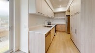 This well-designed 2-bedroom, 1-bathroom unit is located at 3250 Boulevard Henri-Bourassa Est in Montréal, QC. The interior features a clean, modern aesthetic throughout, with light-toned hardwood flooring and crisp white walls that create a bright and airy atmosphere.

The open-concept kitchen and living area forms the heart of the unit. The kitchen is thoughtfully appointed with light wood cabinetry, white countertops, a stainless steel refrigerator, and ample upper and lower storage. Recessed lighting and a tile backsplash complete the contemporary look. The adjoining living room is generously sized, featuring baseboard heating and large sliding glass doors that bring in natural light and provide outdoor access.

Both bedrooms are well-proportioned, with the primary bedroom offering a large window for natural light and easy access to a closet. The second bedroom also features light hardwood floors, white walls, and a sliding closet door. Structural beam details are visible in the ceilings, adding subtle architectural character throughout.

The bathroom is finished in a clean, all-white palette with floor-to-ceiling tiles surrounding a full bathtub and shower combination with chrome fixtures, complemented by tile flooring. Two hallways provide practical flow and connectivity between the rooms. Baseboard heaters are present throughout, ensuring efficient heating across the unit.
