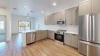 This 680 square foot apartment in Gilbert, Arizona, offers a thoughtfully designed living space that maximizes efficiency and comfort. The single-floor layout comprises one bedroom, one bathroom, and an open-concept living area. The kitchen is a standout feature, boasting a modern L-shaped design with light-colored cabinetry, stainless steel appliances, and ample counter space. The room is illuminated by recessed lighting and features wood-look flooring that extends throughout the main living areas.

The bathroom presents a clean, contemporary aesthetic with a large vanity, ample storage, and a well-lit mirror. The bedroom, measuring 150 square feet, is carpeted for comfort and includes a ceiling fan and large window, allowing for natural light and ventilation. Both the bedroom and main living area offer views of the surrounding greenery through sizeable windows, creating a connection with the outdoors.

The apartment's design emphasizes brightness and spaciousness, with white walls throughout that reflect light and create an airy ambiance. The open floor plan allows for a seamless flow between the kitchen, dining, and living areas, making the space feel larger than its actual square footage. Despite its compact size, the apartment includes a closet for additional storage. Overall, this property presents a modern, low-maintenance living option ideal for singles or couples seeking a contemporary urban lifestyle.