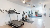 Located at 7700 Lincoln Ave NE in Rio Rancho, New Mexico, this fitness center offers a well-organized, single-floor exercise room designed to support a well-rounded workout routine. The space is laid out efficiently, maximizing every square foot for both cardio and strength training activities.

The cardio zone is equipped with a commercial-grade treadmill, an elliptical trainer, a rowing machine, and a stair climber, all positioned on protective rubber mats. Ceiling fans are mounted throughout to promote air circulation and comfort during workouts. A dedicated free weight area features a full dumbbell rack alongside a weight bench and a multi-function cable machine, catering to a range of strength training exercises. Large wall-mounted mirrors in both the weight and open floor areas enhance the sense of space and allow users to monitor their form.

A designated open mat area with interlocking foam tiles provides ample room for stretching, bodyweight exercises, or functional training. The clean, white walls are adorned with motivational fitness-themed wall art and decals, adding an energetic and encouraging atmosphere. Smooth concrete flooring runs throughout the non-mat areas, contributing to the room's clean, modern aesthetic. Natural light filters in through windows, further brightening the space. Overall, the facility is practical, well-maintained, and thoughtfully equipped for everyday fitness use.