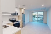Located at 139 S Occidental Blvd in Los Angeles, CA, this modern one-bedroom, one-bathroom unit offers a thoughtfully designed open-concept layout across a single floor. The living and kitchen areas flow seamlessly together, anchored by a large sliding glass door that floods the space with natural light and provides views of the surrounding neighborhood.

The kitchen is well-appointed with a clean, contemporary aesthetic, featuring two-tone cabinetry — white upper cabinets paired with warm wood-tone lower cabinets — complemented by white quartz countertops and a full suite of stainless steel appliances, including a refrigerator, range, microwave, and dishwasher. Light wood-look flooring runs throughout the entire unit, contributing to the bright and cohesive feel.

The bedroom offers a practical layout with a built-in open shelving closet system, providing organized storage space. A second closet with a standard rod is also present. The room is finished with the same light flooring and crisp white walls found throughout the unit.

The bathroom features large-format tile flooring, a full tub-shower combination with sliding glass doors, a wood-toned vanity with a white countertop, and recessed lighting, creating a clean and functional space. Recessed lighting throughout the unit further enhances its modern character.
